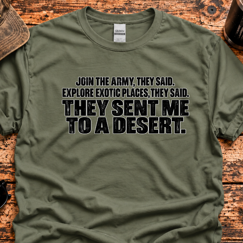 An olive green graphic t-shirt laid flat on a rustic wooden table, surrounded by lifestyle props like a cap, sunglasses, a mug, and a knife. The shirt features a black and white text graphic that reads, 'JOIN THE ARMY, THEY SAID.